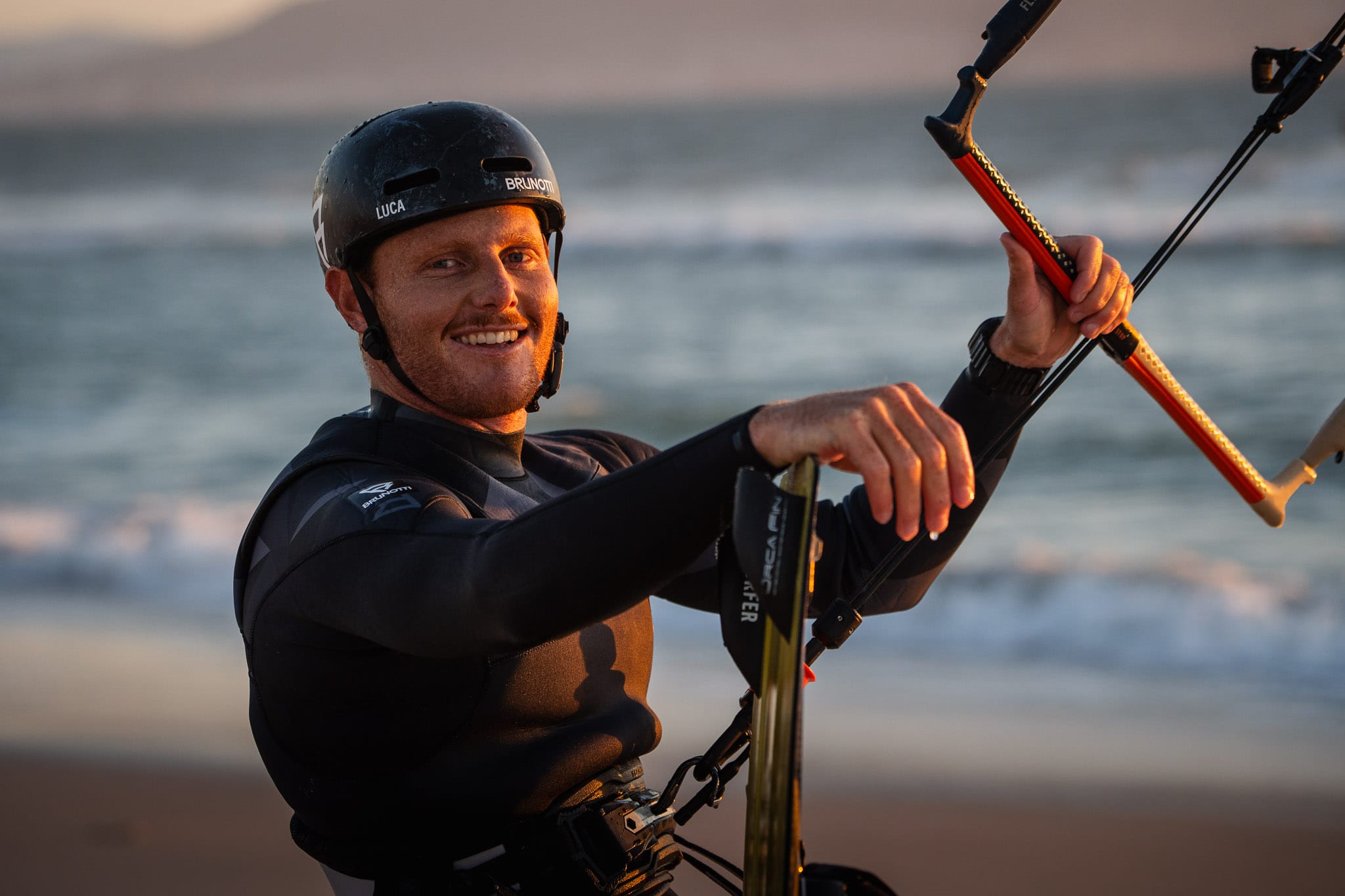 Close-up of the ORCA FIN installed on a kiteboard, with kitesurfer Luca Ceruti standing behind the board